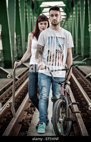 Jeune couple avec Skateboard and BMX bicycle outdoors