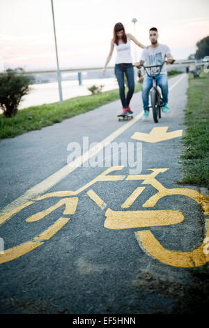 Jeune couple avec Skateboard and BMX bicycle outdoors