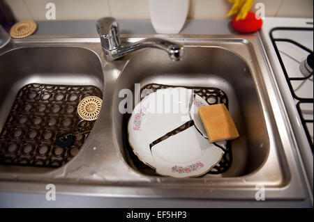Plaque cassée et l'éponge vaisselle sur tapis en plastique dans le lavabo Banque D'Images