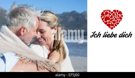 Image composite de smiling couple assis sur la plage, sous couverture Banque D'Images