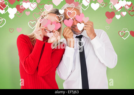 Image composite de silly couple holding cœurs sur les yeux Banque D'Images