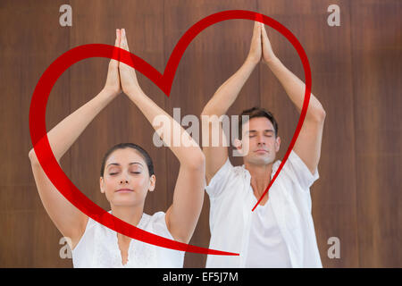Image composite du couple pacifique en blanc faisant du yoga avec les mains levées Banque D'Images