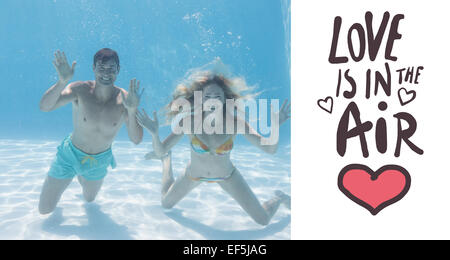 Image composite de cute couple smiling at camera sous l'eau dans la piscine Banque D'Images