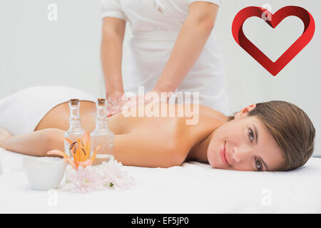 Composite image of young woman receiving back massage au spa center Banque D'Images