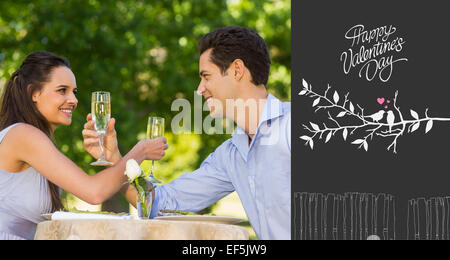 Image composite de couple avec des flûtes à champagne sitting at outdoor cafÃ© Banque D'Images