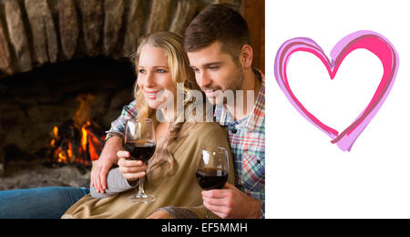 Image composite de couple avec wineglasses devant une cheminée allumée Banque D'Images