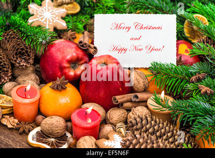 Décoration de Noël avec des bougies allumées et carte de voeux. Les fruits, les noix, les épices et les cookies Banque D'Images