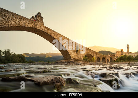 Pont bossu. Bobbio. Emilia-Romagna. L'Italie. Le vieux pont "Gobbo' avec ses archs sur la rivière au coucher du soleil. Banque D'Images