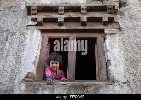 Leh, Ladakh, Inde. Jeune fille à la fenêtre de sa maison Banque D'Images