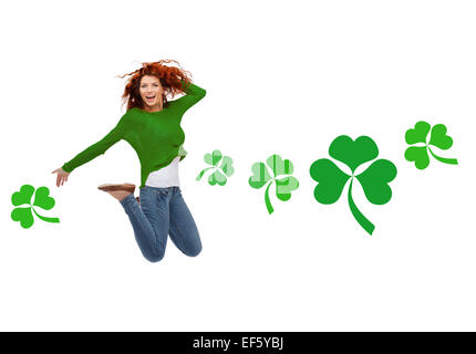 Smiling teenage girl jumping in air avec shamrock Banque D'Images