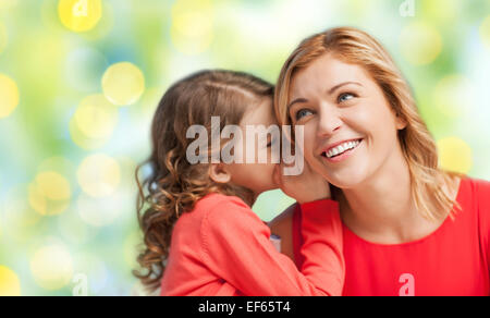 Fille heureuse whispering gossip à sa mère Banque D'Images