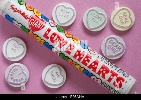 Paquet de Swizzels Matlow cœur d'amour géant avec des bonbons individuels sur fond rose - idéal pour la Saint-Valentin, Saint-Valentin - bonbons à coeur de loveheart Banque D'Images