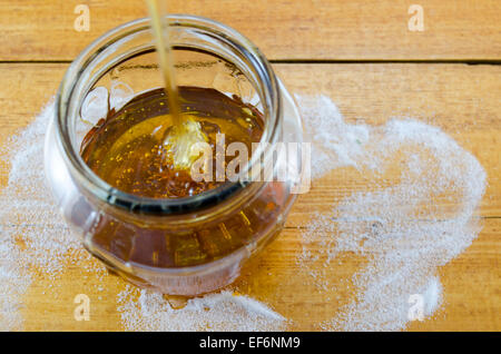 Dégoulinant de miel foncé dans un bocal de verre Banque D'Images