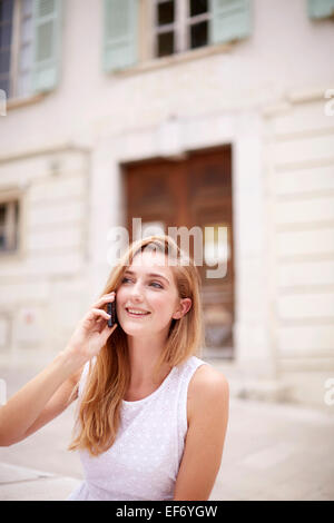 Jeune femme en vacances assis par la mairie de la ville de La Colle sur Loup dans le sud de la France en utilisant son smartphone Banque D'Images