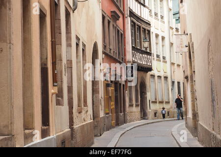 Un Français parler sur un téléphone mobile, la marche avec un petit garçon, dans une étroite rue française. Banque D'Images