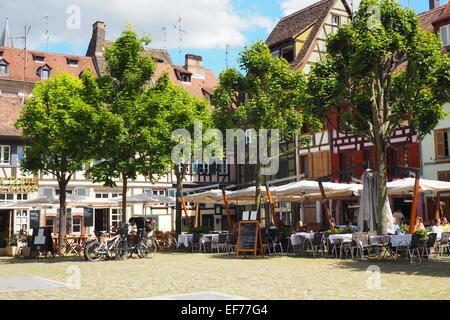 Manger en plein air entre les bâtiments à ossature de bois en place du marché Gayot, une place médiévale à Strasbourg. Banque D'Images