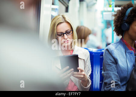 Businesswoman using digital tablet on train Banque D'Images