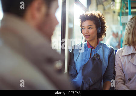 Woman listening to headphones on train Banque D'Images