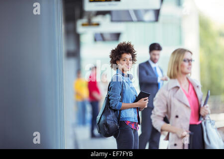 Woman holding digital tablet et en attente de train en gare Banque D'Images