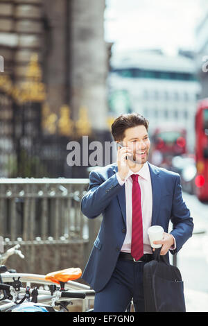 Businessman talking on cell phone on city sidewalk Banque D'Images