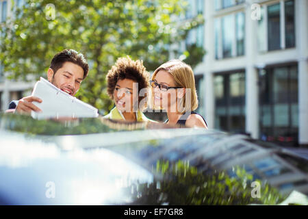 Business people reading paperwork près de voiture Banque D'Images