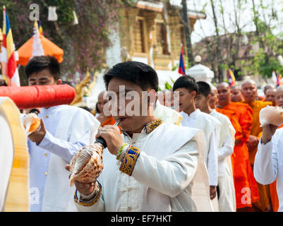 Un jeune homme soufflant dans la coquille de conque à Luang Prabang Lao Mai Rp lors de fête du Nouvel An. Banque D'Images