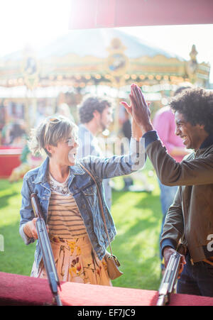Jeune couple giving high five dans amusement park Banque D'Images