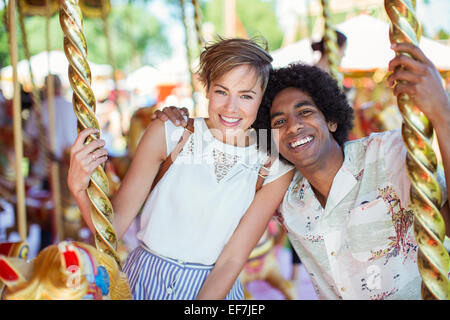 Jeune couple multiracial sur carrousel en amusement park Banque D'Images