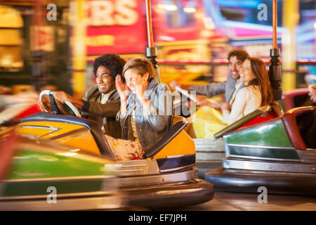 Groupe d'amis s'amuser sur bouclier avant en voiture dans un parc d'attractions Banque D'Images
