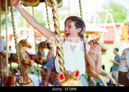 Cheerful woman sitting on horse sur carrousel en amusement park Banque D'Images