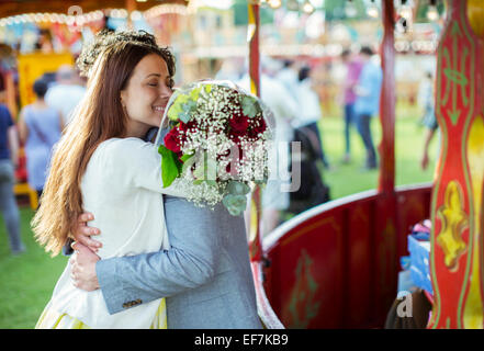 Woman holding bouquet et embrassant son petit ami dans un parc d'attractions Banque D'Images