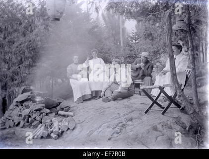 Meubles anciens c1905 photo, groupe d'adultes camping tea pot en fonte sur le feu et de lanternes de papier japonais. Emplacement est probablement le Massachusetts, USA. Banque D'Images