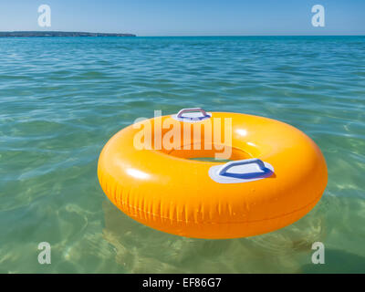 Anneau en caoutchouc orange vide flottant dans la mer Banque D'Images