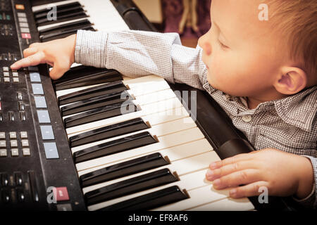 Enfance heureuse et de la musique. Petit garçon enfant enfants jouant sur le clavier numérique noir piano midi Synthétiseur instrument de musique Banque D'Images