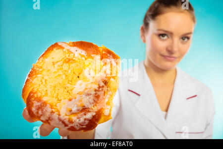 Une mauvaise alimentation l'excès de concept. Nutritionniste disent non à un dessert sucré. Femme médecin Diététicien holding sweet bun recom Banque D'Images