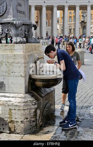 Un adolescent d'une fontaine d'eau potable à St Peter's square, Vatican, Rome, Italie. Banque D'Images