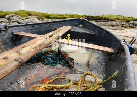 Smiley jaune Homme en vacances dans les Hébrides extérieures- Ici il est assis dans une chaloupe sur la plage environ pour attraper la rame et aller à la pêche Banque D'Images