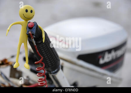 Smiley jaune Homme en vacances dans les îles Hébrides - Ici il est sur le point de démarrer le moteur hors bord sur son bateau de pêche Banque D'Images