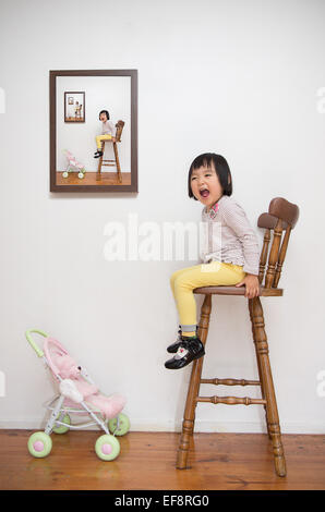 Fille assise sur le tabouret à côté de l'image elle-même Banque D'Images