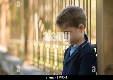 Portrait of a sad boy leaning against balustrades métalliques Banque D'Images