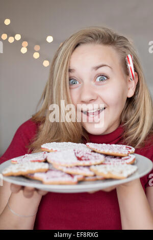 Smiling girl (14-15) holding plate of Christmas Cookies