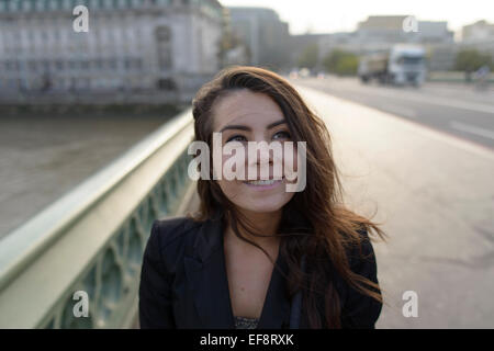 Femme souriante debout sur le pont de Westminster, à la recherche, Londres, Angleterre, Royaume-Uni Banque D'Images