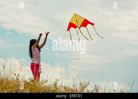 Portrait of Girl (8-9) flying kite on hill Banque D'Images