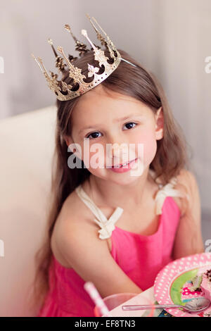 Girl (4-5) dans la couronne et avec le gâteau d'anniversaire Banque D'Images