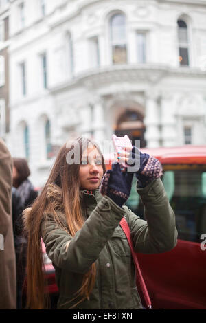 Teenage girl (14-15) en prenant la photo sur téléphone mobile à l'aide de la rue Banque D'Images