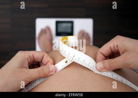 Pregnant woman measuring belly sur l'échelle de poids Banque D'Images