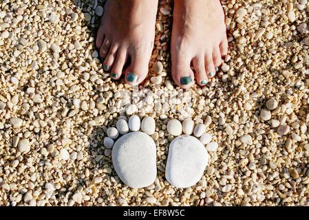 Pierres en forme de pieds devant les pieds de la femme, Stara Baska, Krk, Croatie Banque D'Images