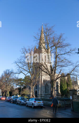 Un vieux monsieur avec un bâton de marche passe devant la face de l'église de Tous les Saints à Oakham, Rutland. Banque D'Images