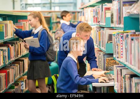 Teenage students using computer in college library Banque D'Images