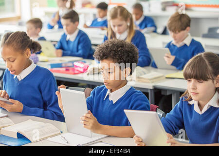 Les enfants de l'école élémentaire avec digital tablets in classroom Banque D'Images